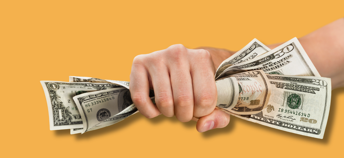 A hand gripping a fistful of cash